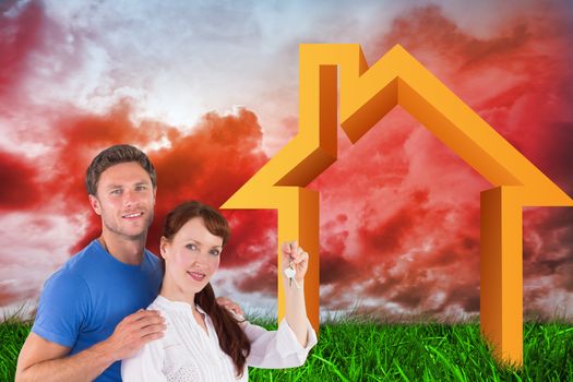 Couple holding keys to home against green grass under red cloudy sky