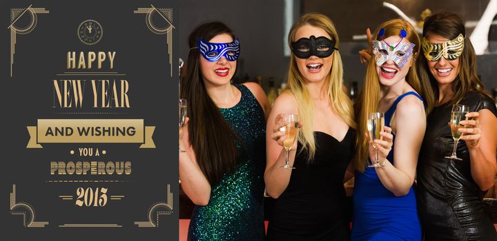 Laughing friends wearing masks holding champagne glasses against art deco new year greeting