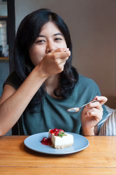 Young beautiful asian woman enjoy with a cake in cafe