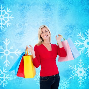 Happy blonde holding shopping bags against blue snow flake pattern design
