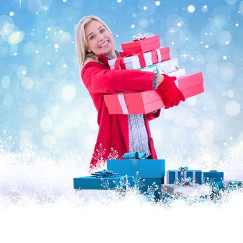Festive blonde holding many gifts against blue abstract light spot design