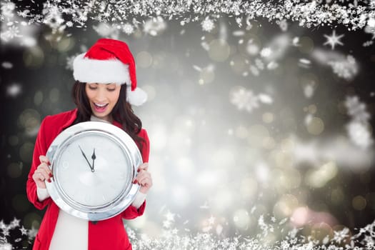 Excited brunette holding a clock against black abstract light spot design