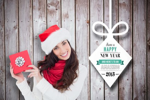 Joyful brunette presenting christmas gift against christmas decorations over wood