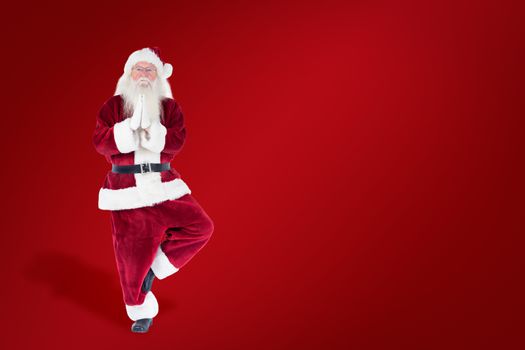 Father Christmas doing some yoga against red background