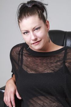 thirty something woman wearing a transparent shirt, sitting in a love seat