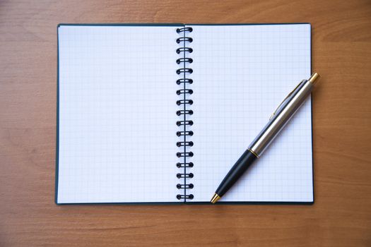 paper notebook with pen on wooden background