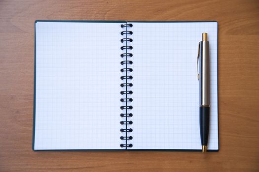 paper notebook with pen on wooden background