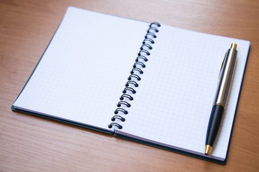 paper notebook with pen on wooden background