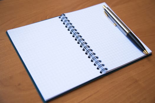 paper notebook with pen on wooden background