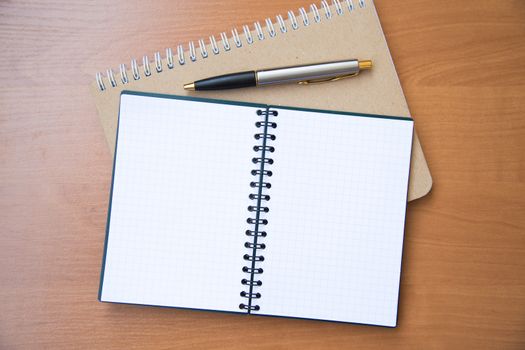 paper notebook with pen on wooden background