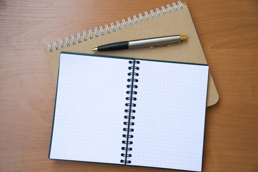 paper notebook with pen on wooden background