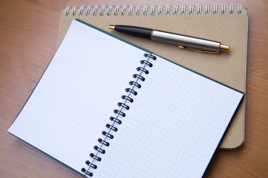 paper notebook with pen on wooden background