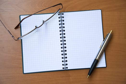 paper notebook with pen on wooden background