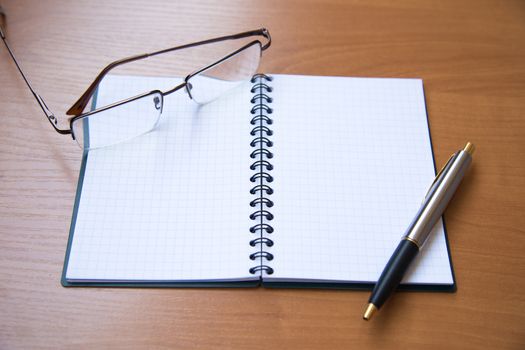 paper notebook with pen on wooden background