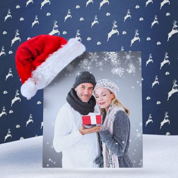 happy winter couple with gift against blue reindeer pattern