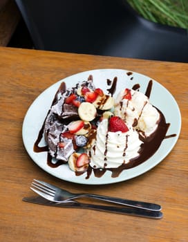 Ice cream, banana, strawberry, raspberry, chocolate waffles with chocolate sauce 