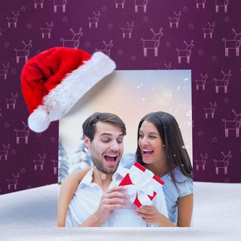 woman surprising boyfriend with gift against purple reindeer pattern