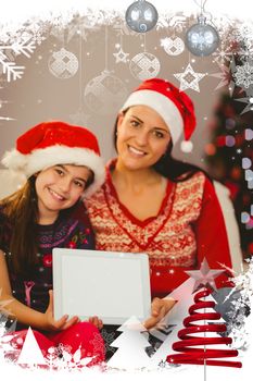 Festive mother and daughter showing tablet screen against christmas themed frame with decoration