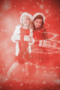 Festive little girls smiling at camera with gifts against glittering christmas tree design