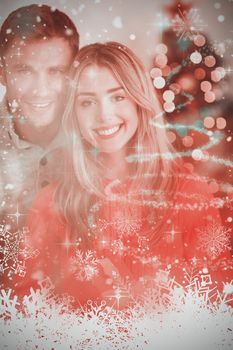 Happy couple holding each other against glittering christmas tree design