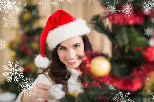 Beauty brunette decorating a christmas tree against snowflakes