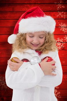 Festive little girl holding baubles against snowflake pattern on red planks