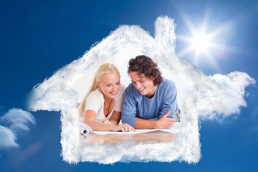 Smiling couple getting ready to move in a new house against bright blue sky with clouds