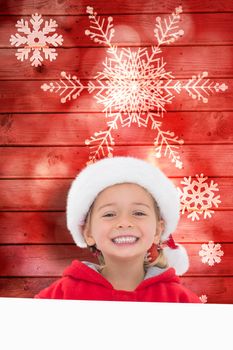 Festive little girl showing poster against snowflake pattern on red planks