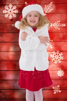 Festive little girl smiling at camera against snowflake pattern on red planks