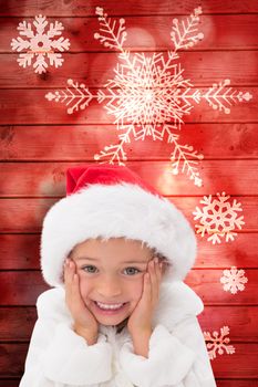 Cute little girl wearing santa hat  against snowflake pattern on red planks