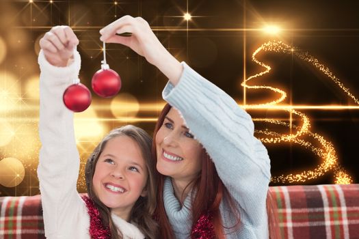 Mother and daughter holding baubles against christmas light design