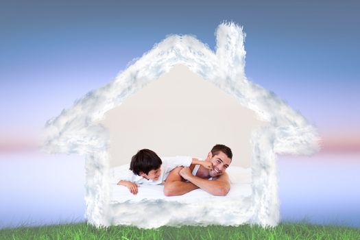Father and his son having fun on a bed against green grass under blue and purple sky