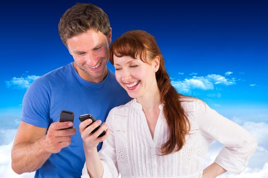 Couple using their mobile phones against bright blue sky over clouds