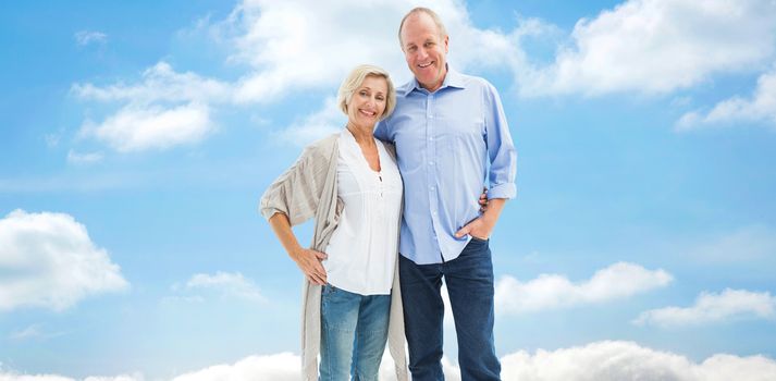 Happy mature couple hugging and smiling against cloudy sky
