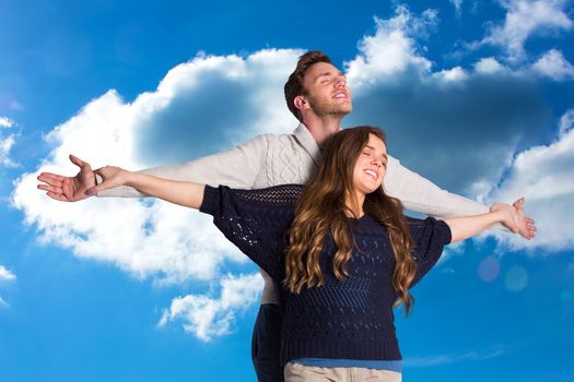 Romantic young couple with arms out against cloudy sky