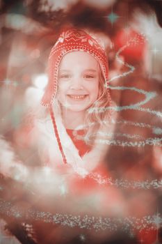 Festive little girl in hat and scarf against glittering christmas tree design