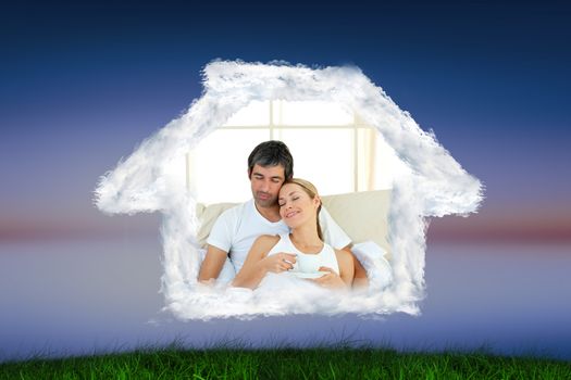 Positive couple drinking coffee lying in the bed against green grass under blue and purple sky