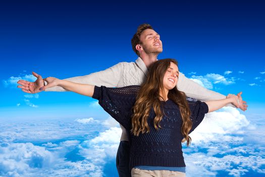 Romantic young couple with arms out against mountain peak through clouds