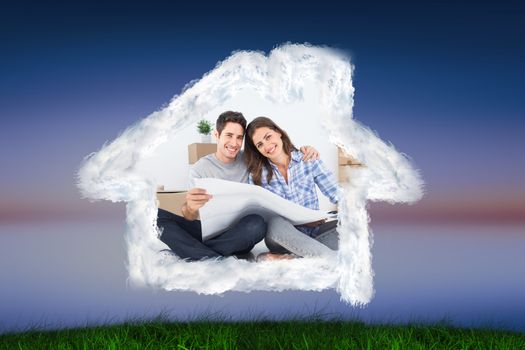 man and woman holding house plans  against green grass under blue and purple sky