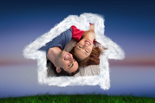 Two friends looking into the sky while lying on a quilt against green grass under blue and purple sky