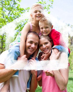 Happy parents giving their children piggyback ride against house outline in clouds