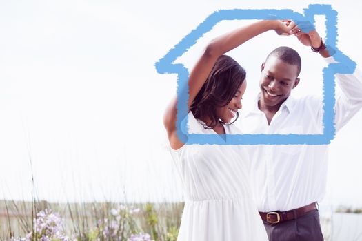 Romantic couple dancing and smiling against house outline