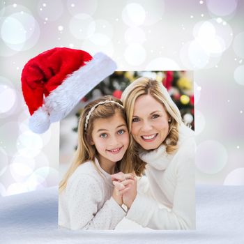 Festive mother and daughter beside christmas tree against purple abstract light spot design