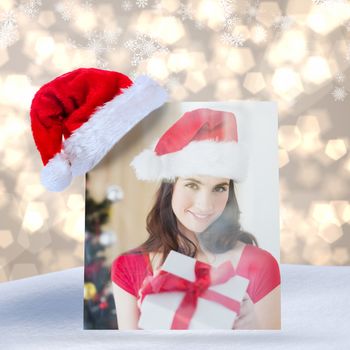 Beauty brunette showing gift at christmas against light glowing dots design pattern