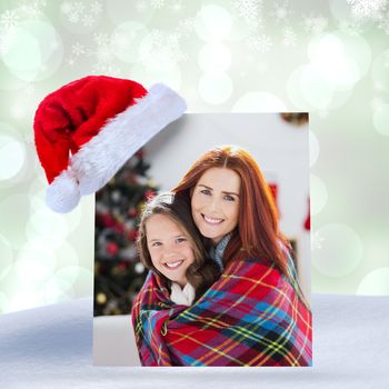 Festive mother and daughter wrapped in blanket against grey abstract light spot design