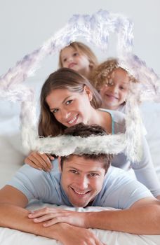 Portrait of a joyful family lying on each other against house outline in clouds