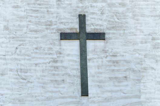 White plastered wall with a large metal cross.