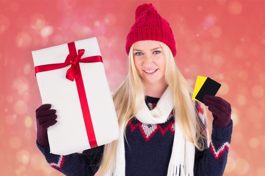 Festive blonde holding a gift against red abstract light spot design
