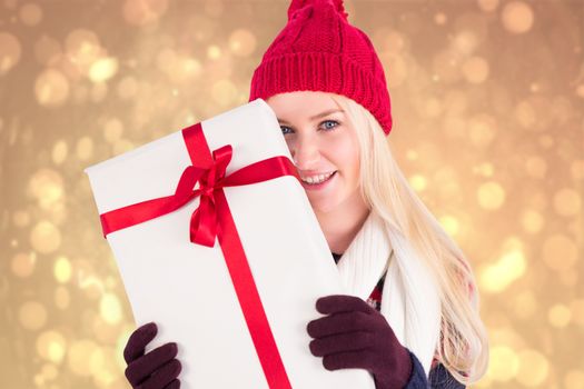 Festive blonde holding a gift against yellow abstract light spot design