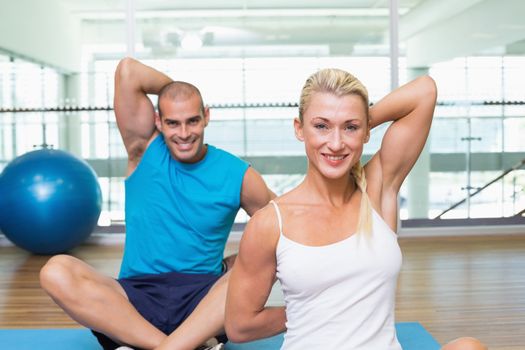 Portrait of happy young couple stretching hands behind back in yoga class